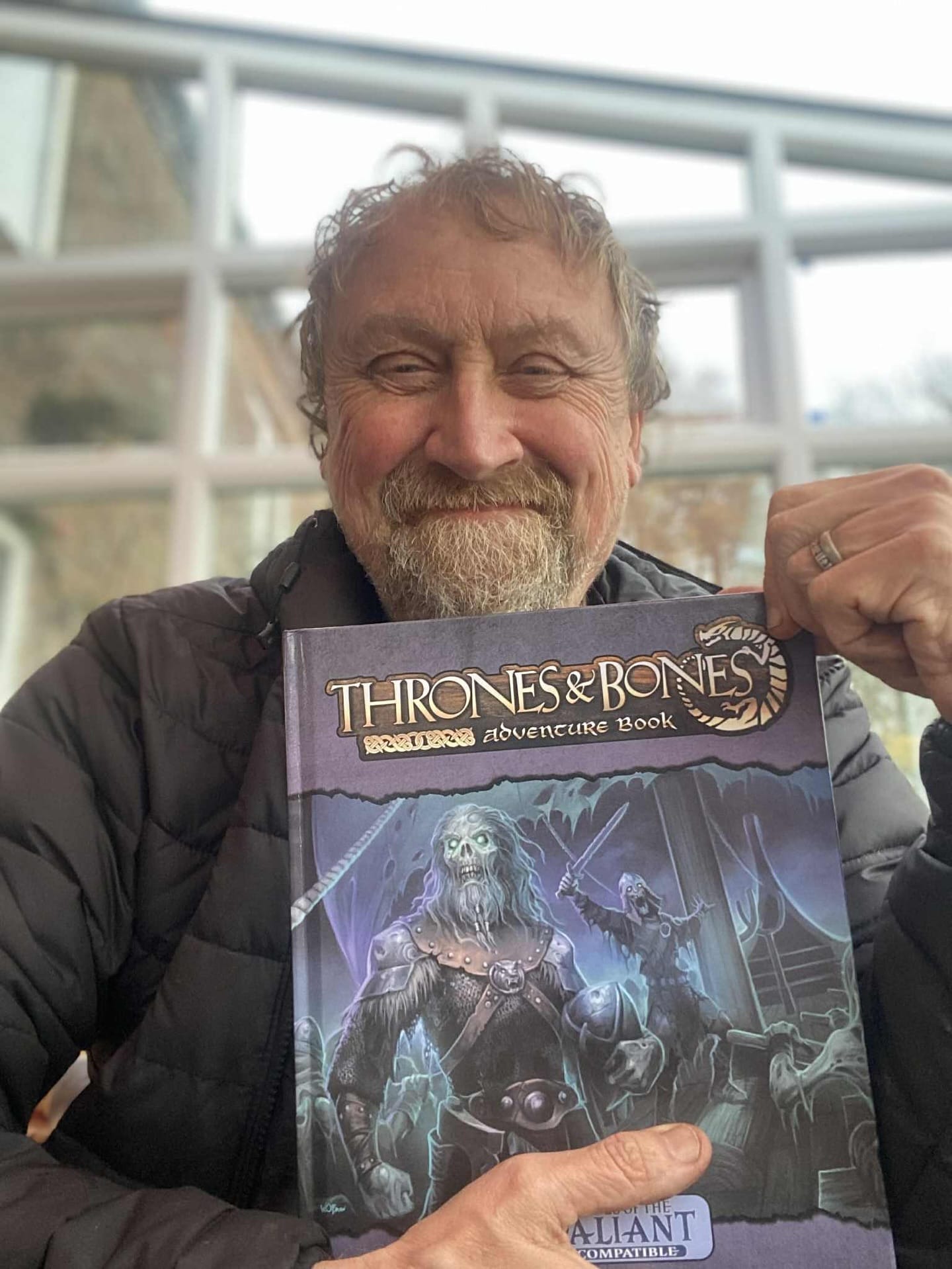 Richard Pett, smiling, holding up the hardcover.