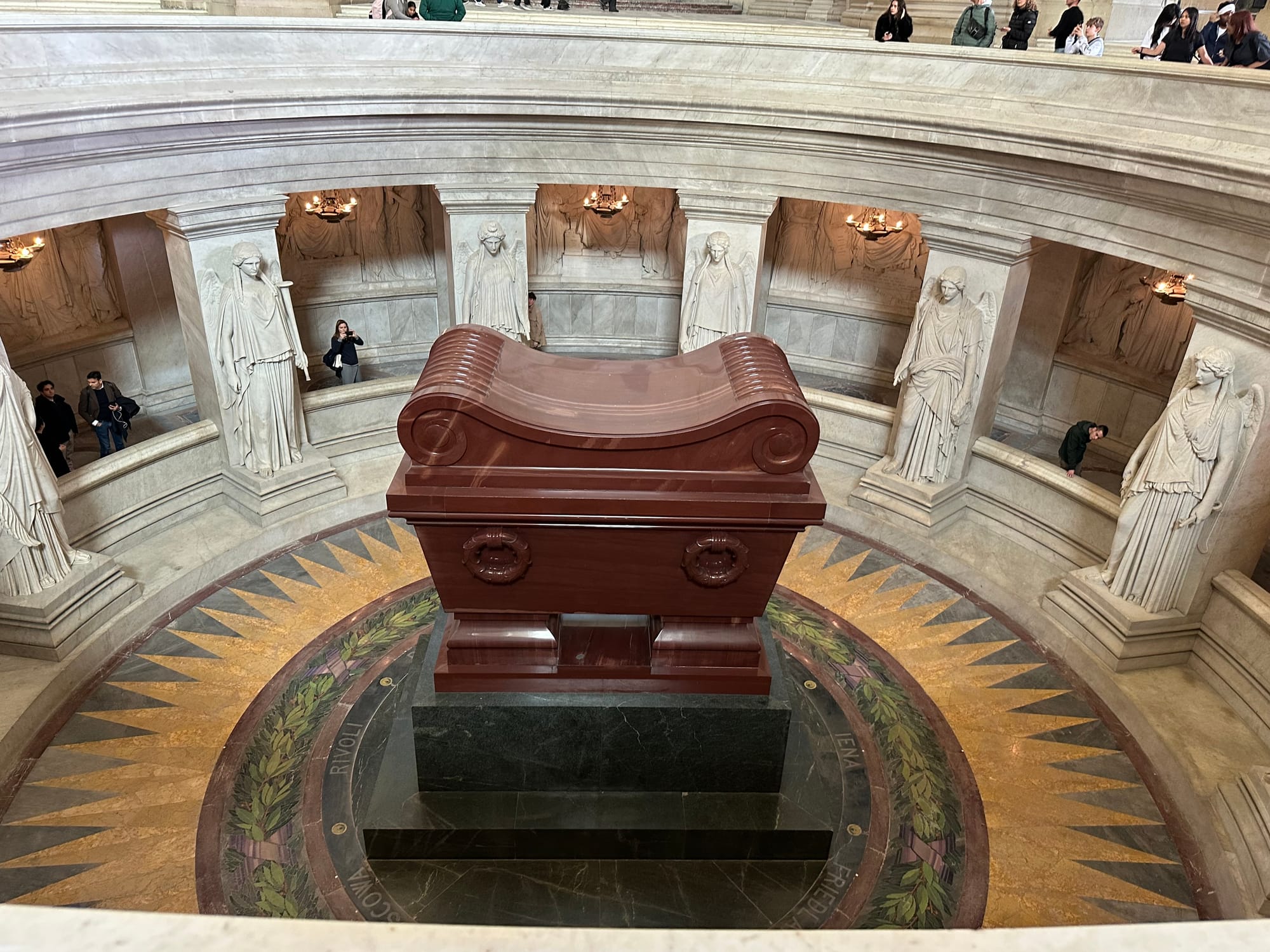 An enormous sarcophagus in a round chamber with a balcony above. The sarcophagus sits on two slabs of different colors.